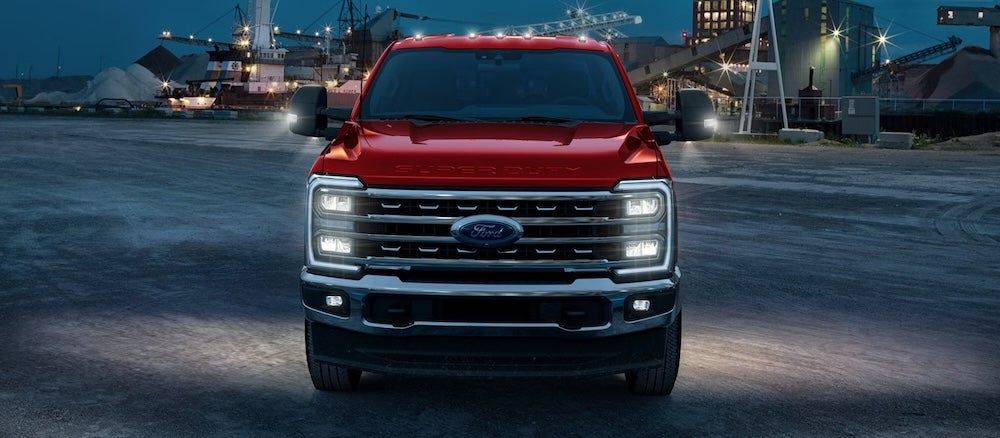 A red 2026 Ford Super Duty pickup truck parked at a work site at night